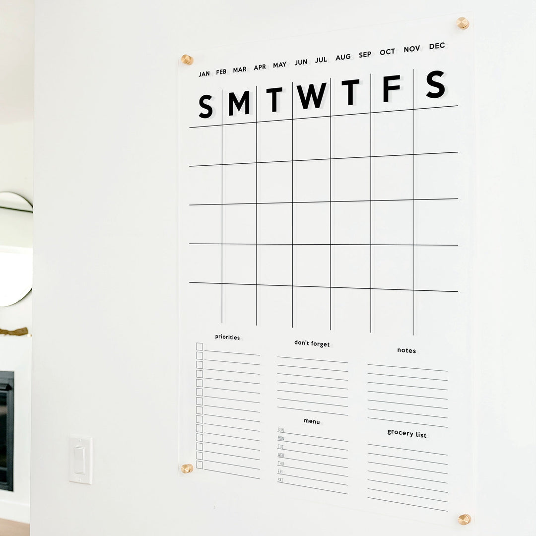 A Dry-erase family command center made of acrylic hanging on the wall