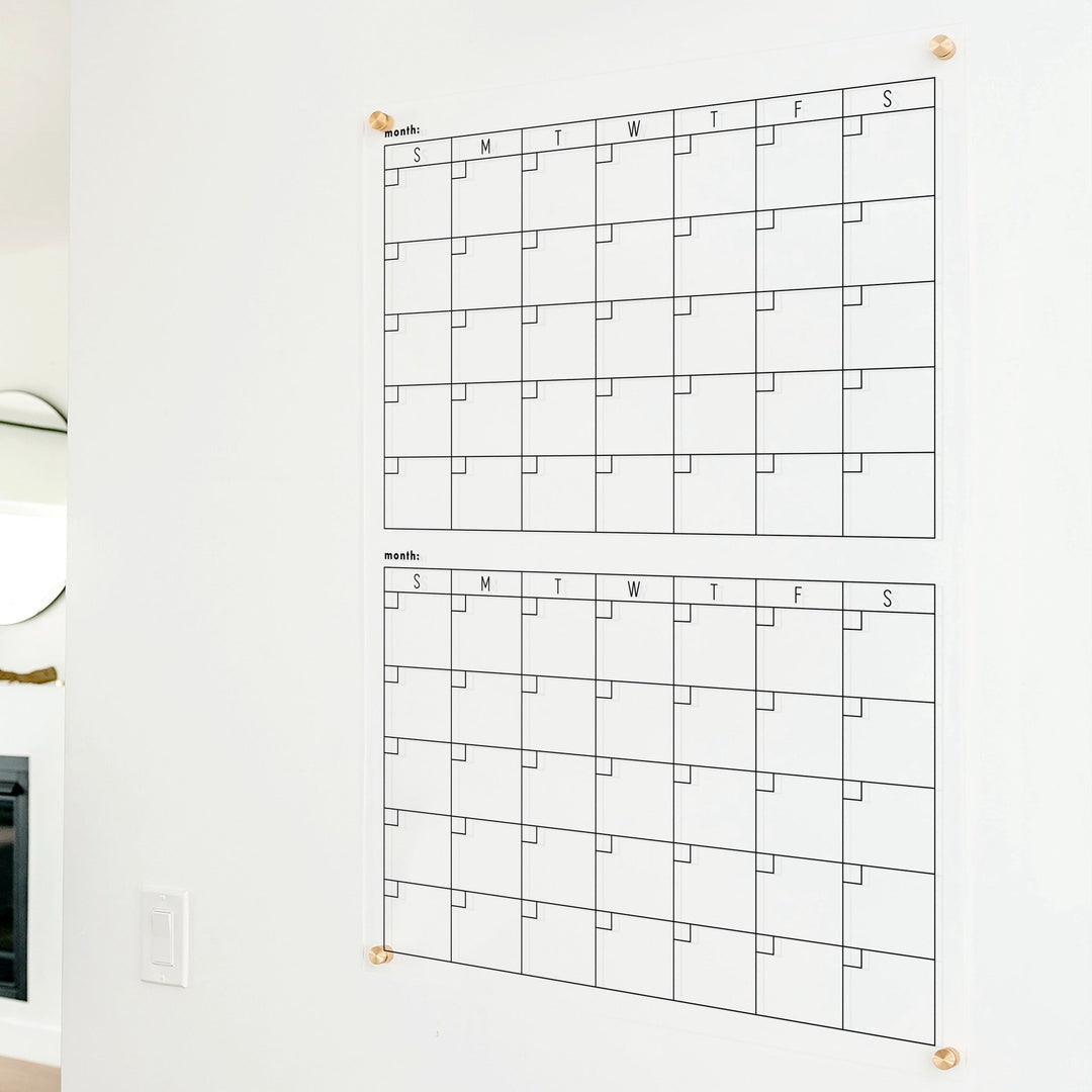 A Dry-erase acrylic calendar with a two month design format hanging on the wall