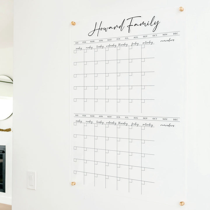 A Dry-erase acrylic calendar with a two month design format hanging on the wall