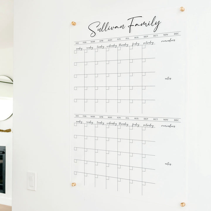 A Dry-erase acrylic calendar with a two month design format hanging on the wall