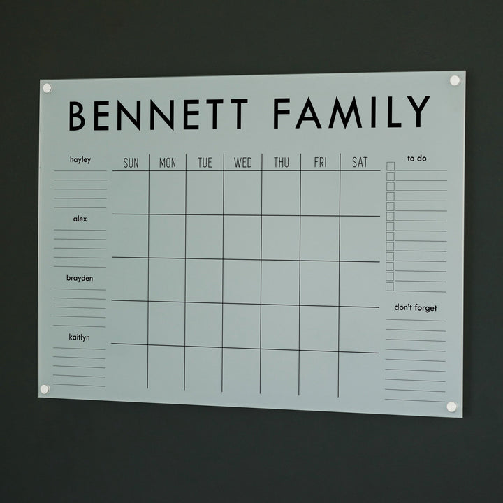 A Dry-erase family command center made of acrylic hanging on the wall