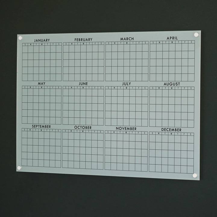 A dry-erase yearly calendar made of acrylic hanging up on the wall
