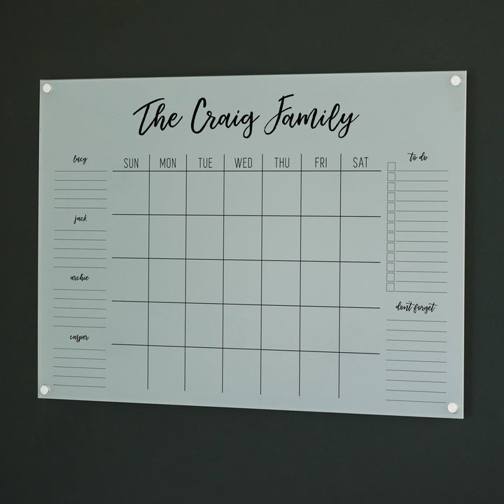 A Dry-erase family command center made of acrylic hanging on the wall