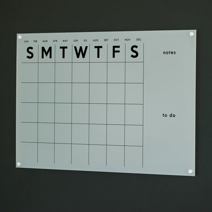 A Dry-erase monthly calender made of acrylic hanging on the wall