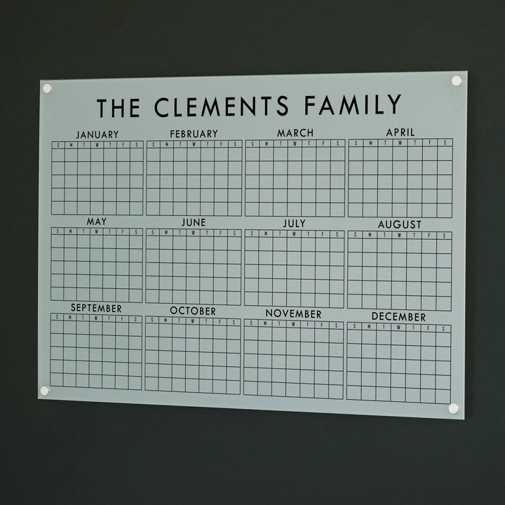 A dry-erase yearly calendar made of acrylic hanging up on the wall