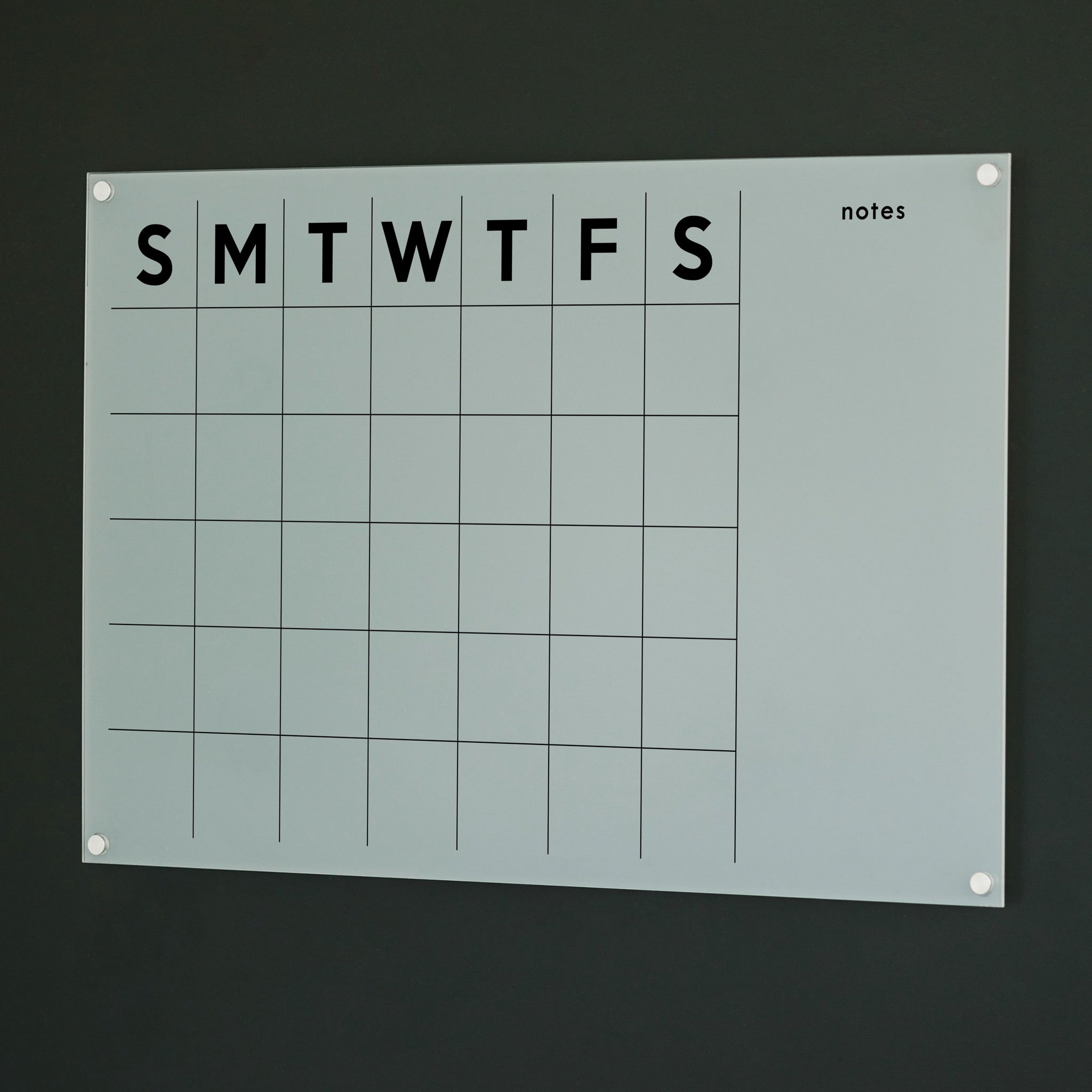 A Dry-erase monthly calender made of acrylic hanging on the wall