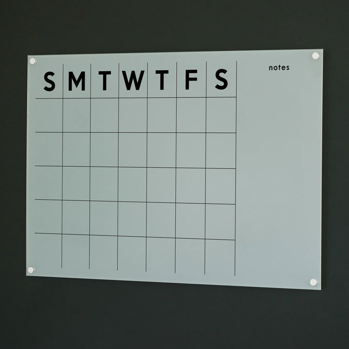 A Dry-erase monthly calender made of acrylic hanging on the wall