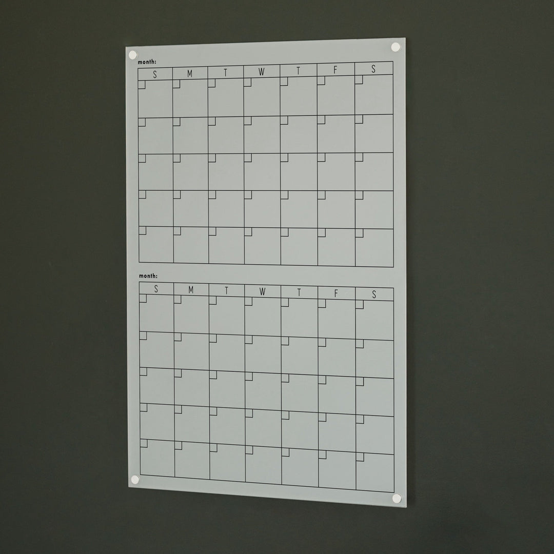 A Dry-erase acrylic calendar with a two month design format hanging on the wall