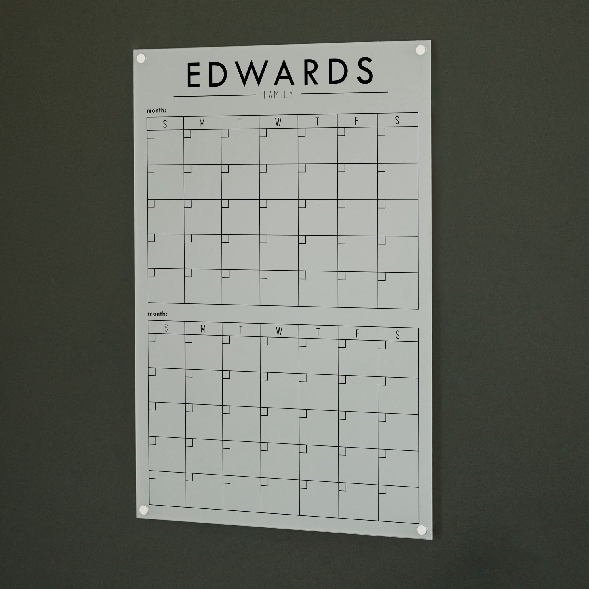 A Dry-erase acrylic calendar with a two month design format hanging on the wall