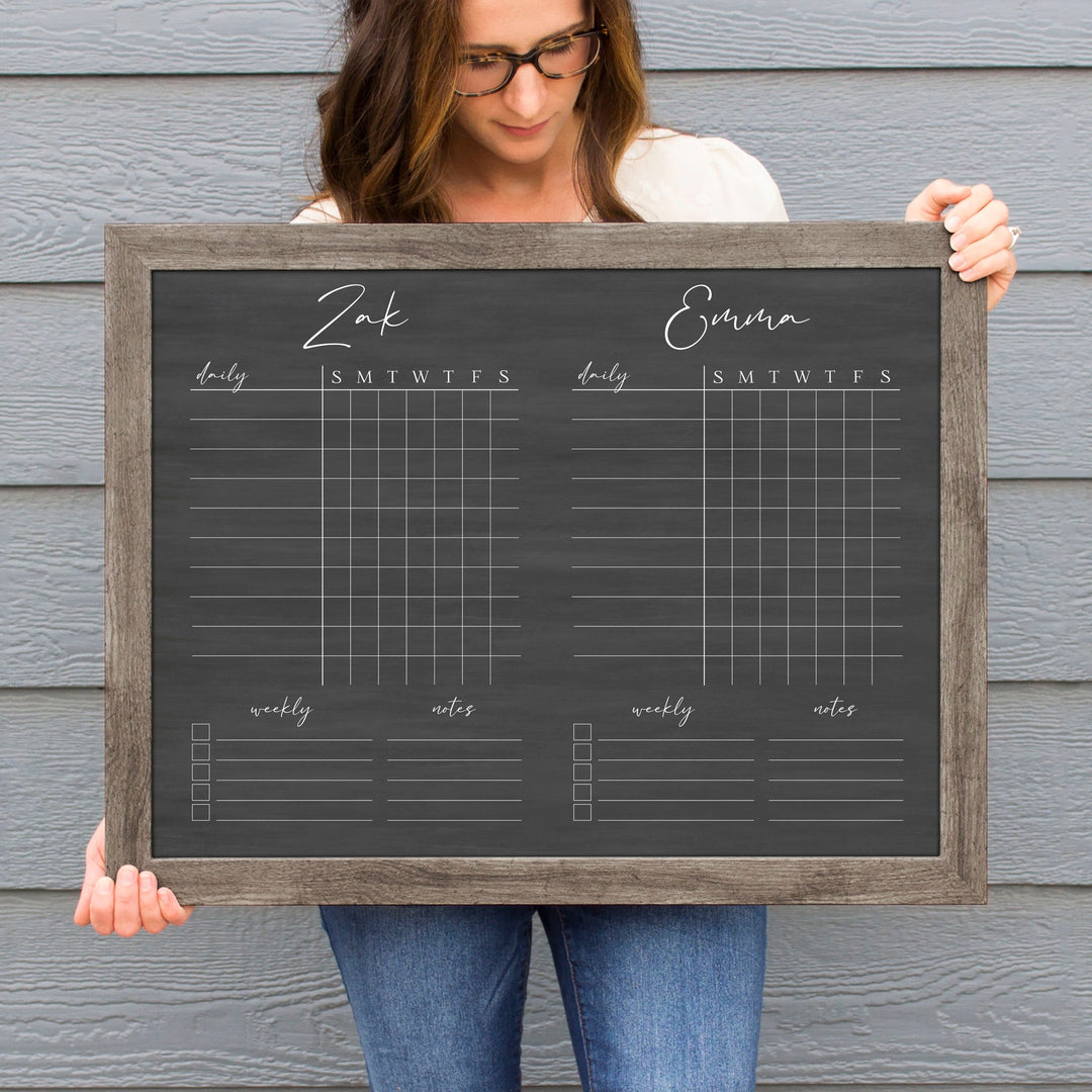 A framed dry-erase chore chart with a chalkboard look hanging on the wall