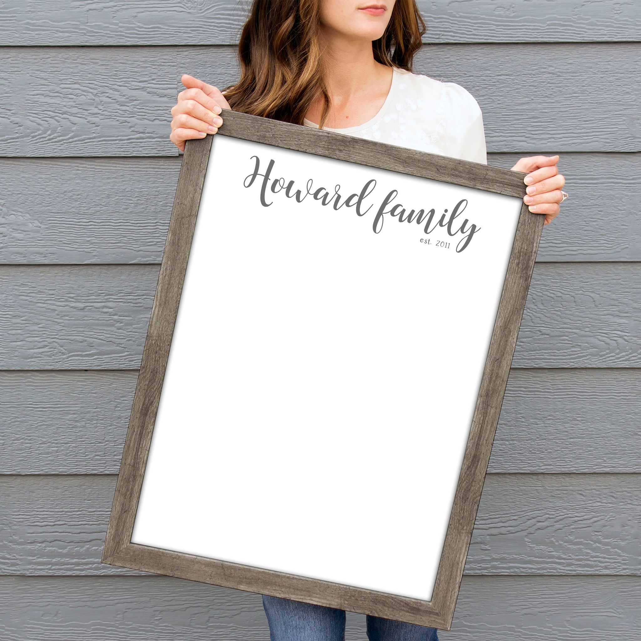 A framed whiteboard calendar with a two month design format hanging on the wall