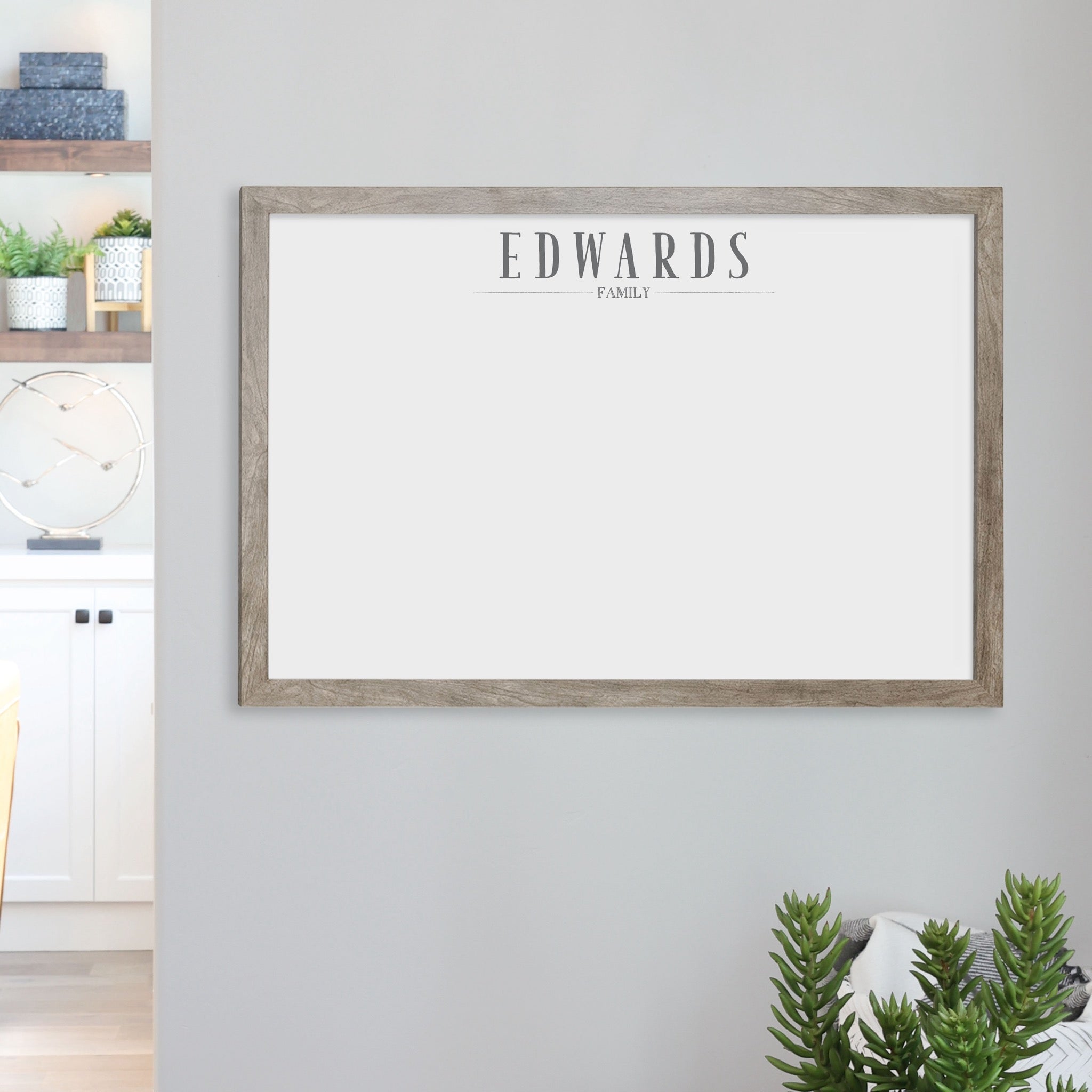 A framed whiteboard calendar with a two month design format hanging on the wall