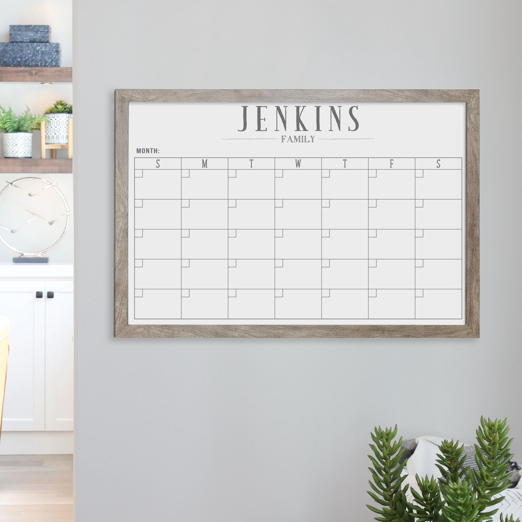 A framed whiteboard monthly calender hanging on the wall