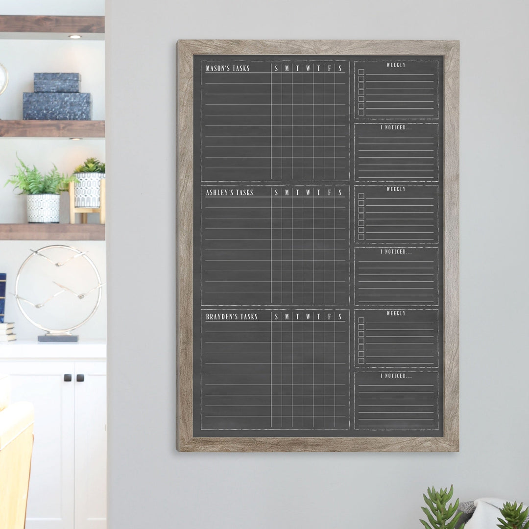 A framed dry-erase chore chart with a chalkboard look hanging on the wall