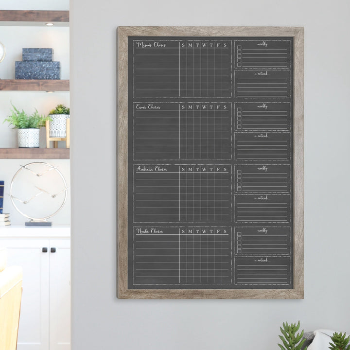 A framed dry-erase chore chart with a chalkboard look hanging on the wall