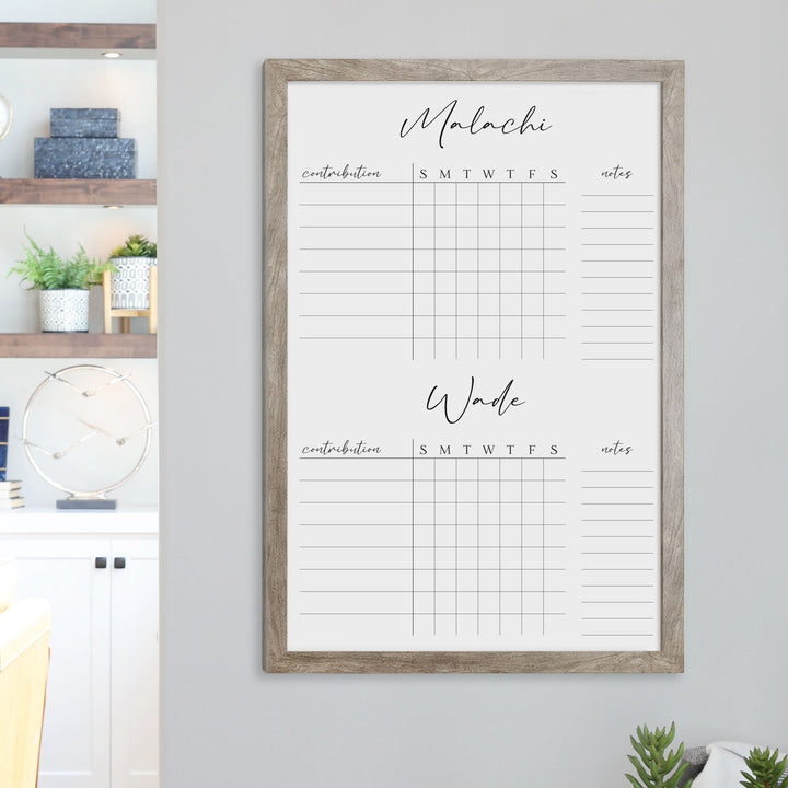 A framed whiteboard chore chart hanging on the wall