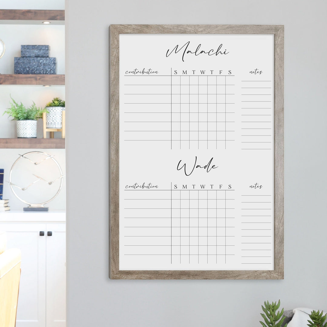 A framed whiteboard chore chart hanging on the wall