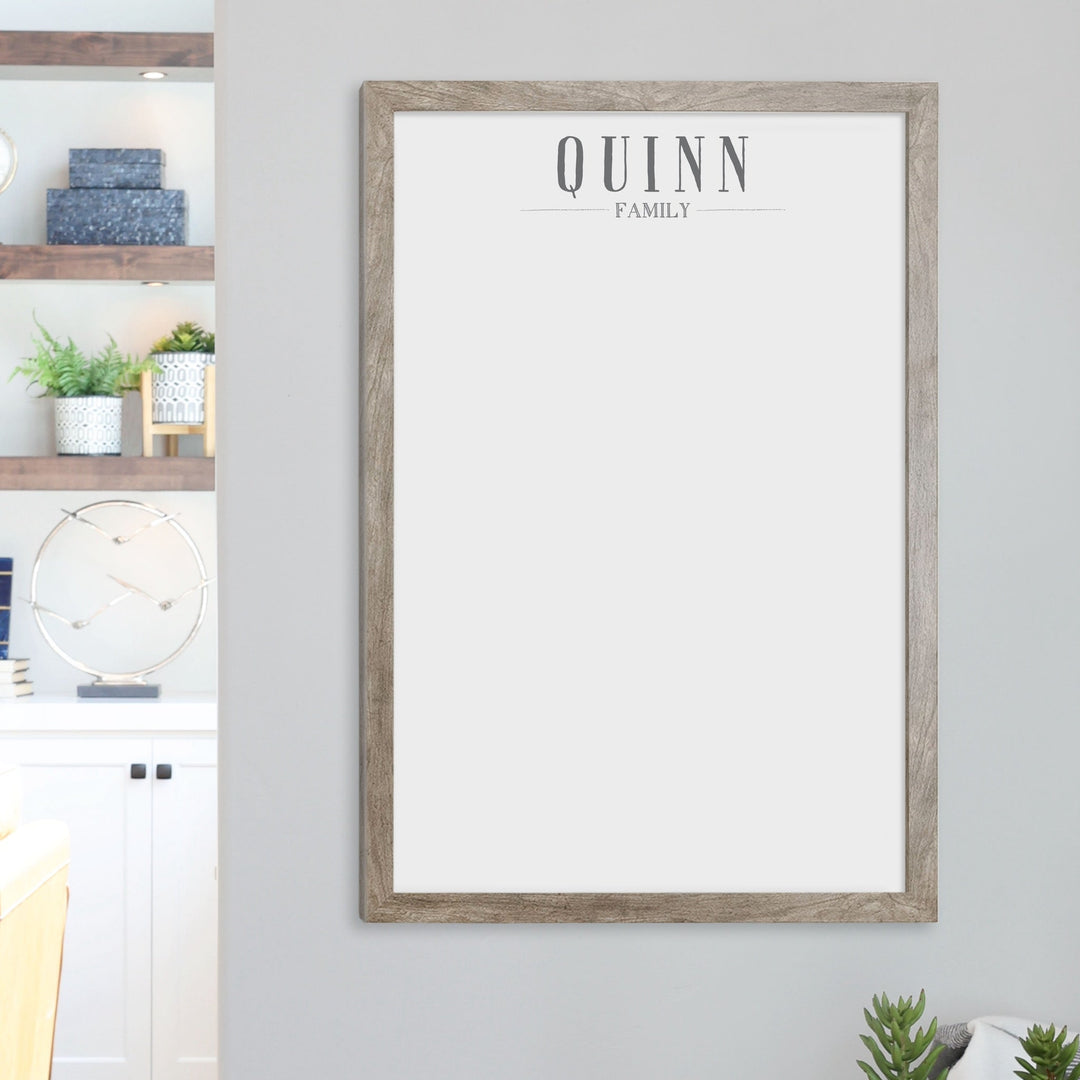 A framed whiteboard calendar with a two month design format hanging on the wall