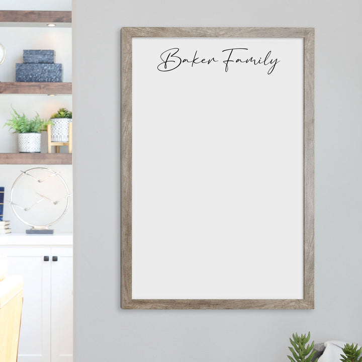A framed whiteboard calendar with a two month design format hanging on the wall