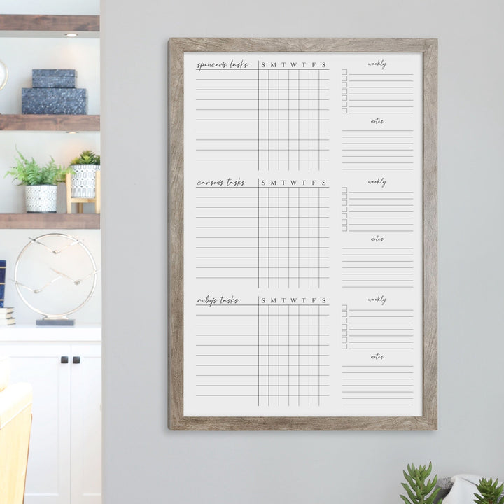A framed whiteboard chore chart hanging on the wall