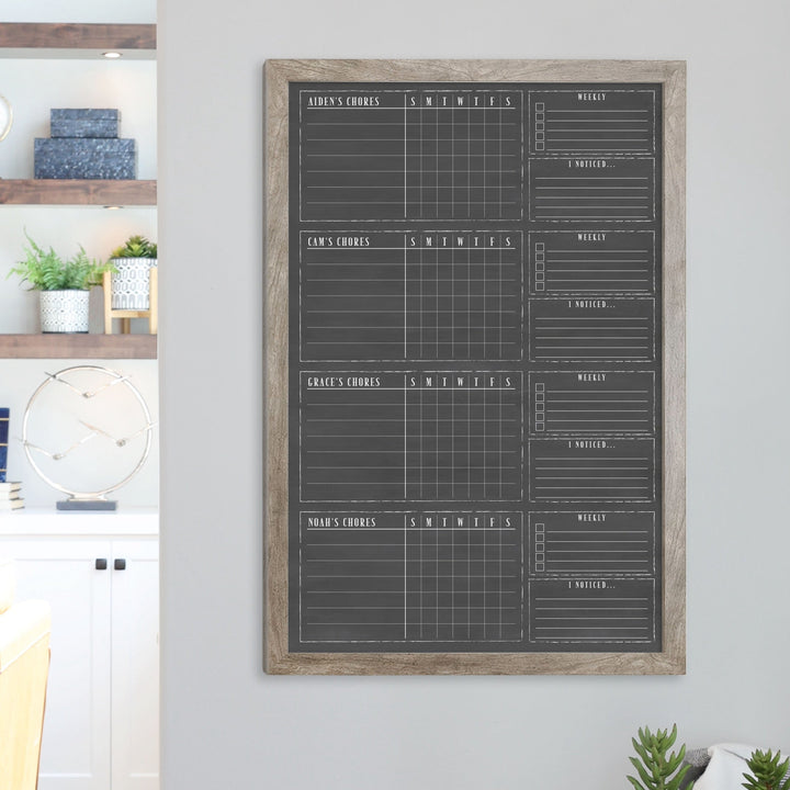 A framed dry-erase chore chart with a chalkboard look hanging on the wall