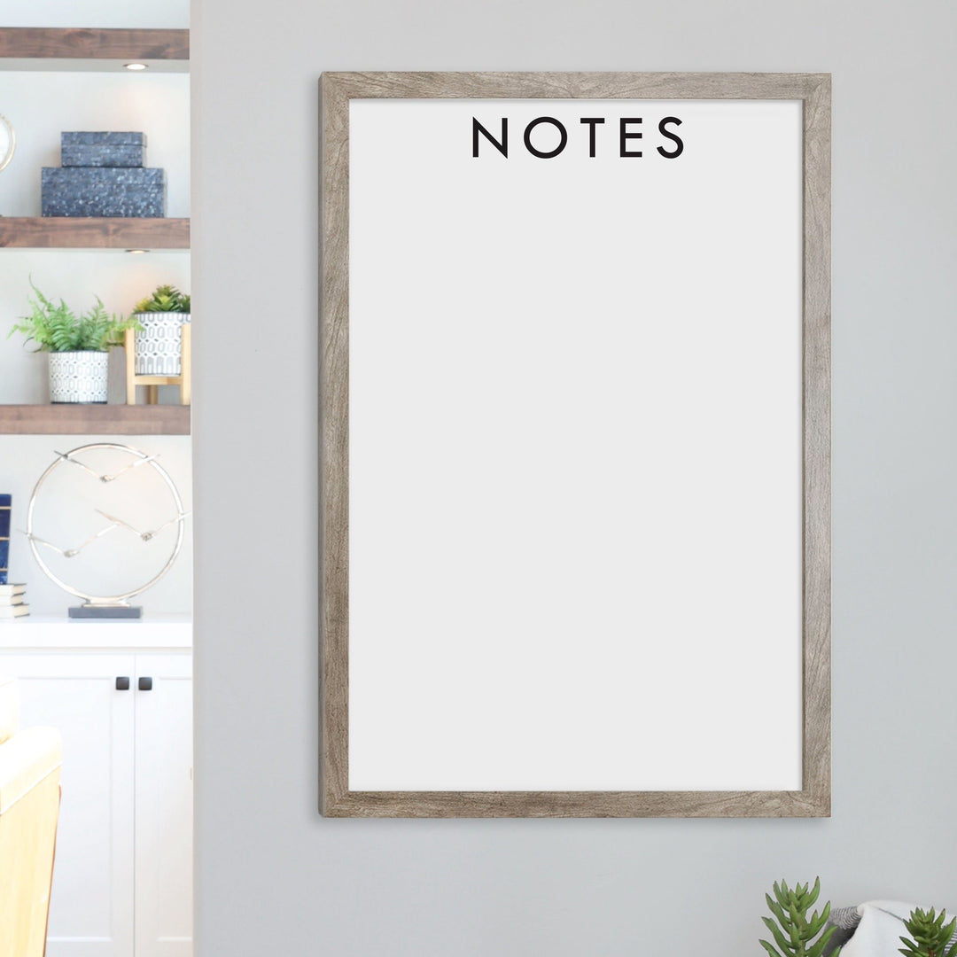 A framed whiteboard calendar with a two month design format hanging on the wall