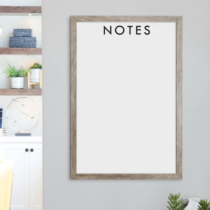A framed whiteboard calendar with a two month design format hanging on the wall