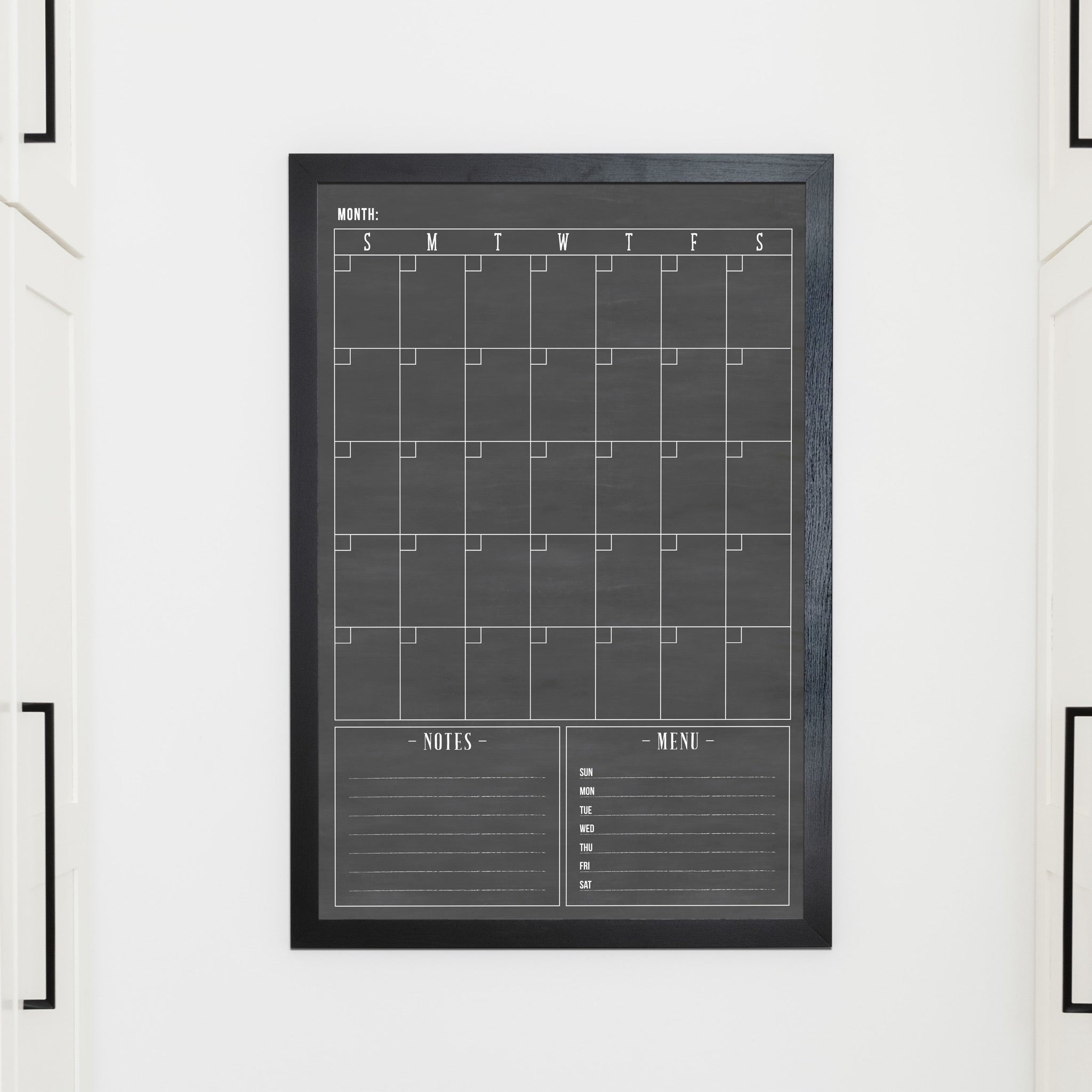 A framed whiteboard monthly calender hanging on the wall