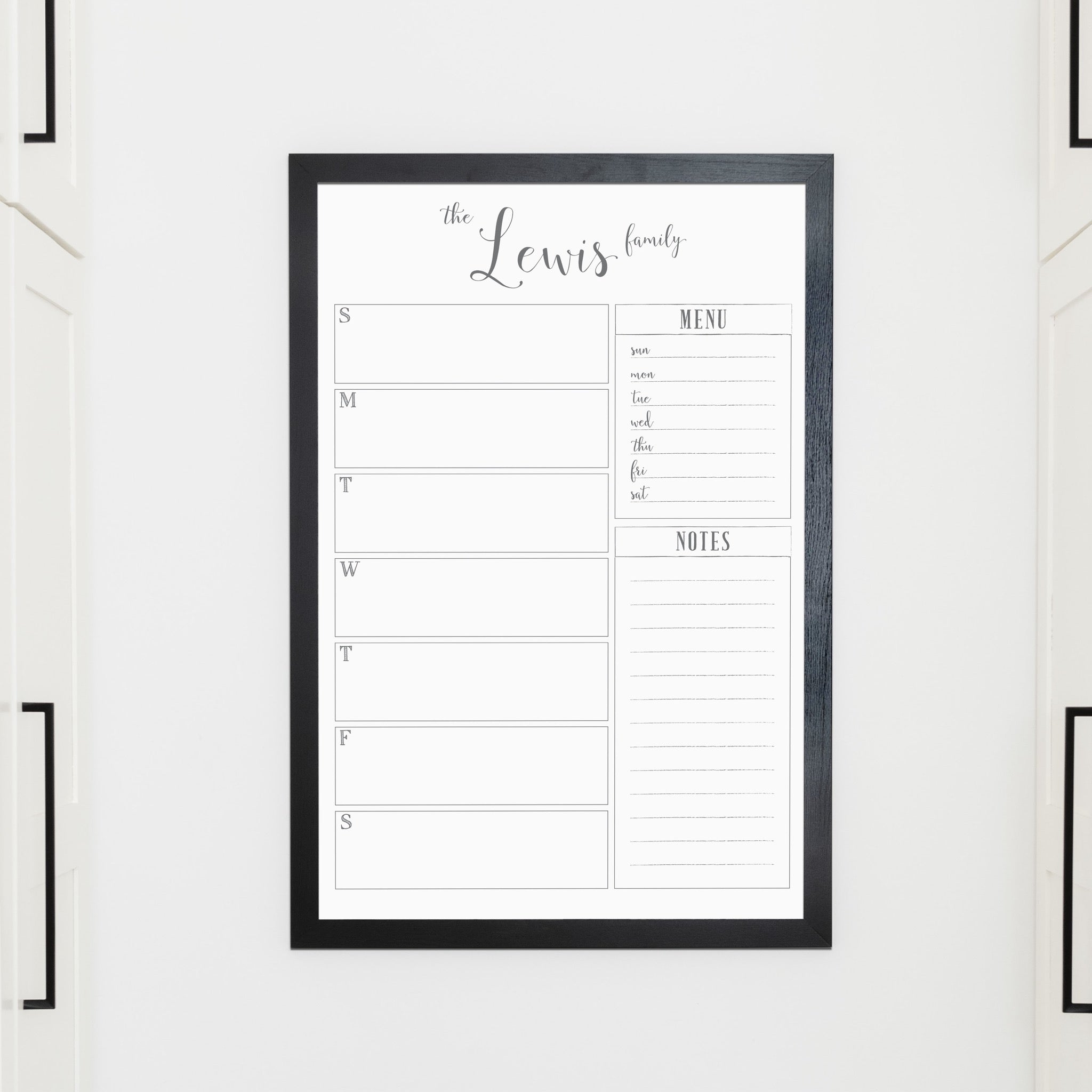 A framed whiteboard weekly calender hanging on the wall