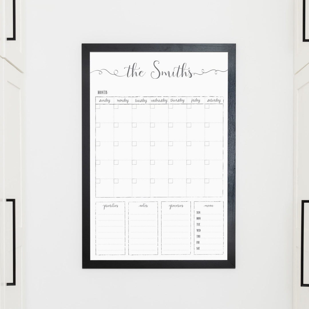 A framed whiteboard family command center hanging on the wall