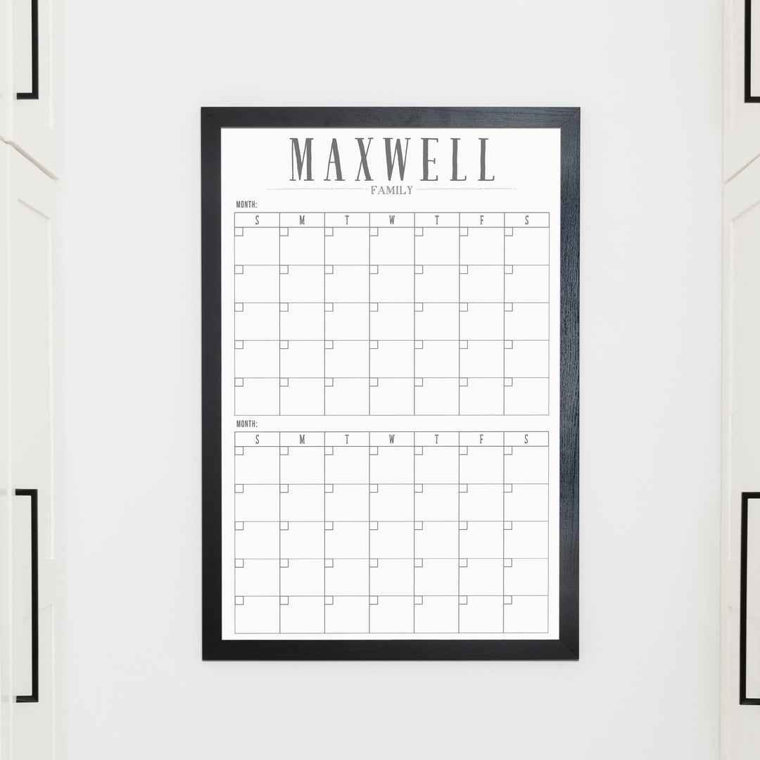 A framed whiteboard calendar with a two month design format hanging on the wall
