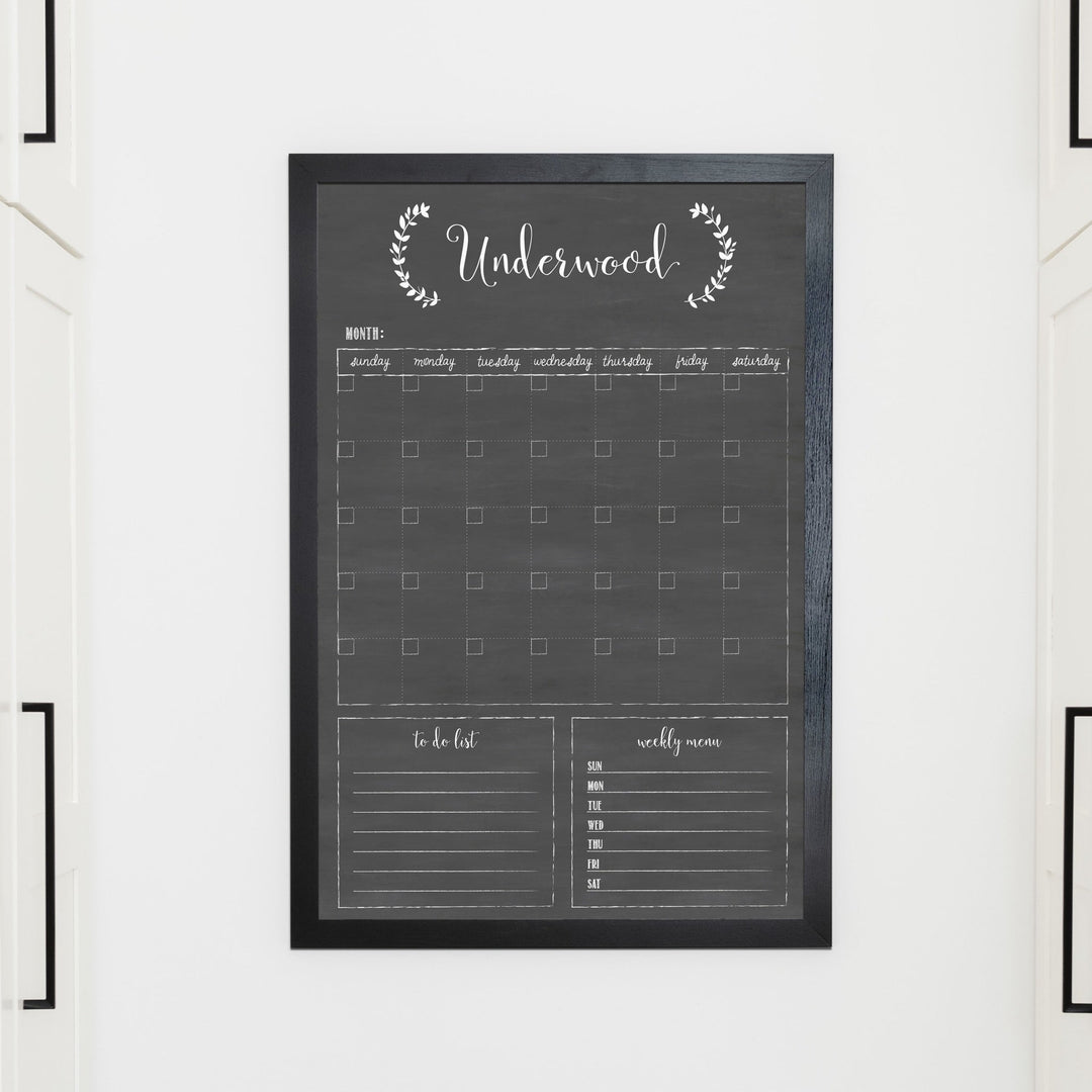 A framed whiteboard monthly calender hanging on the wall