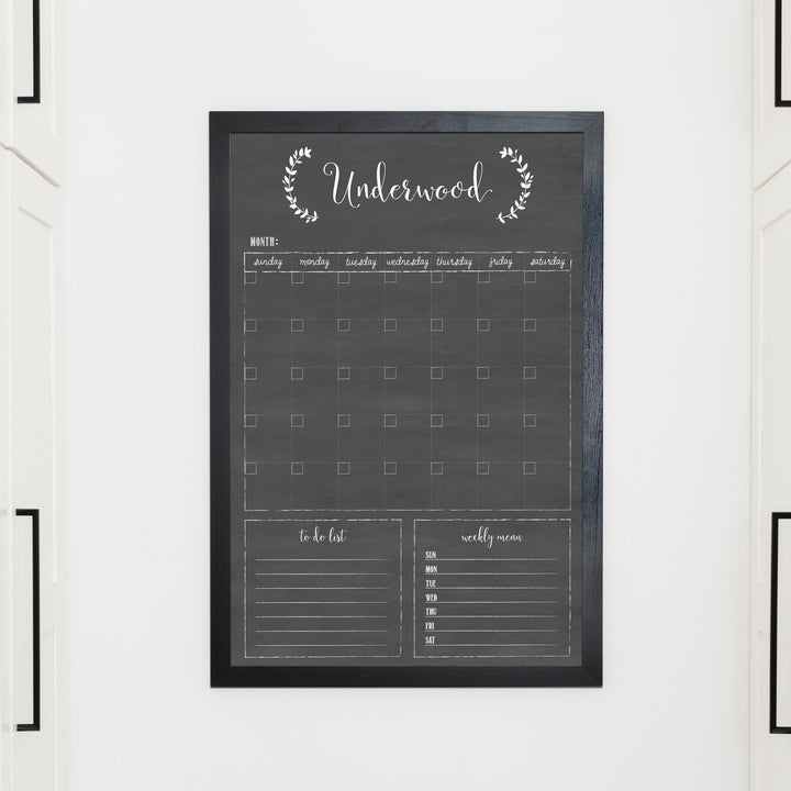 A framed whiteboard monthly calender hanging on the wall