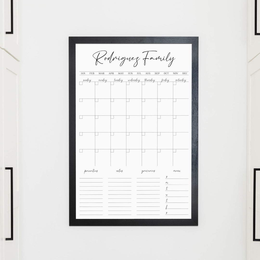 A framed whiteboard family command center hanging on the wall