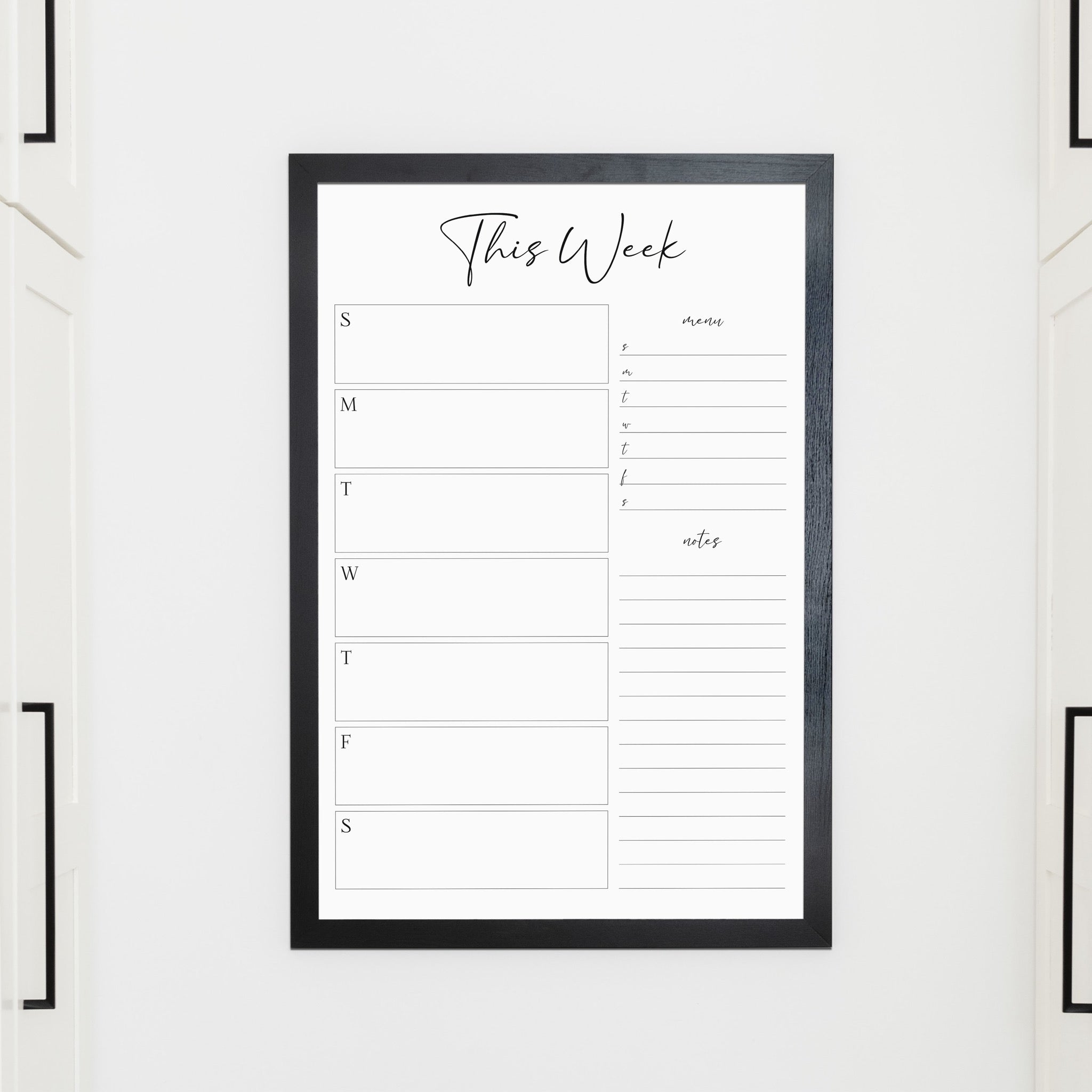 A framed whiteboard weekly calender hanging on the wall