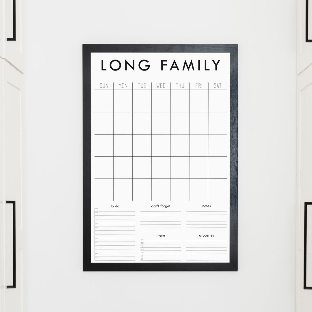 A framed whiteboard family command center hanging on the wall