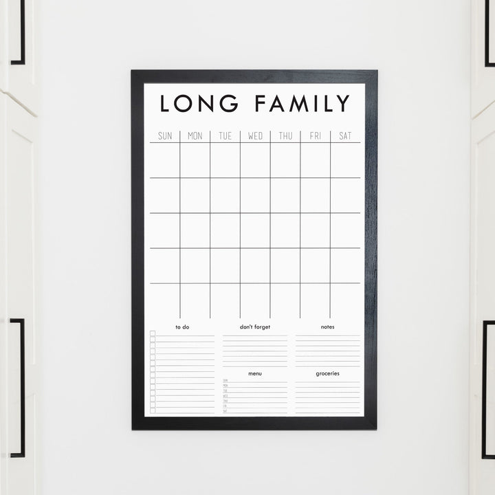 A framed whiteboard family command center hanging on the wall