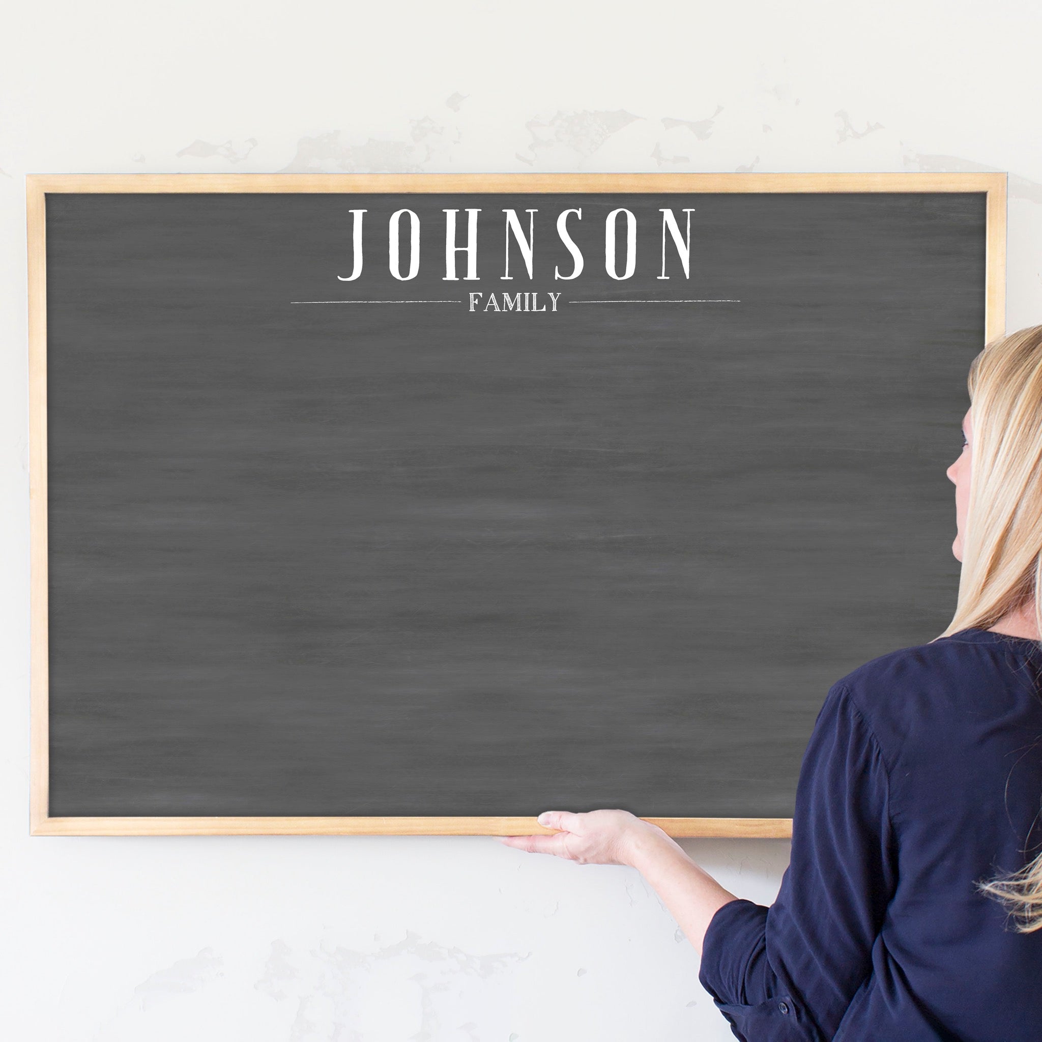 A framed dry-erase chalkboard calendar with a two month design format hanging on the wall