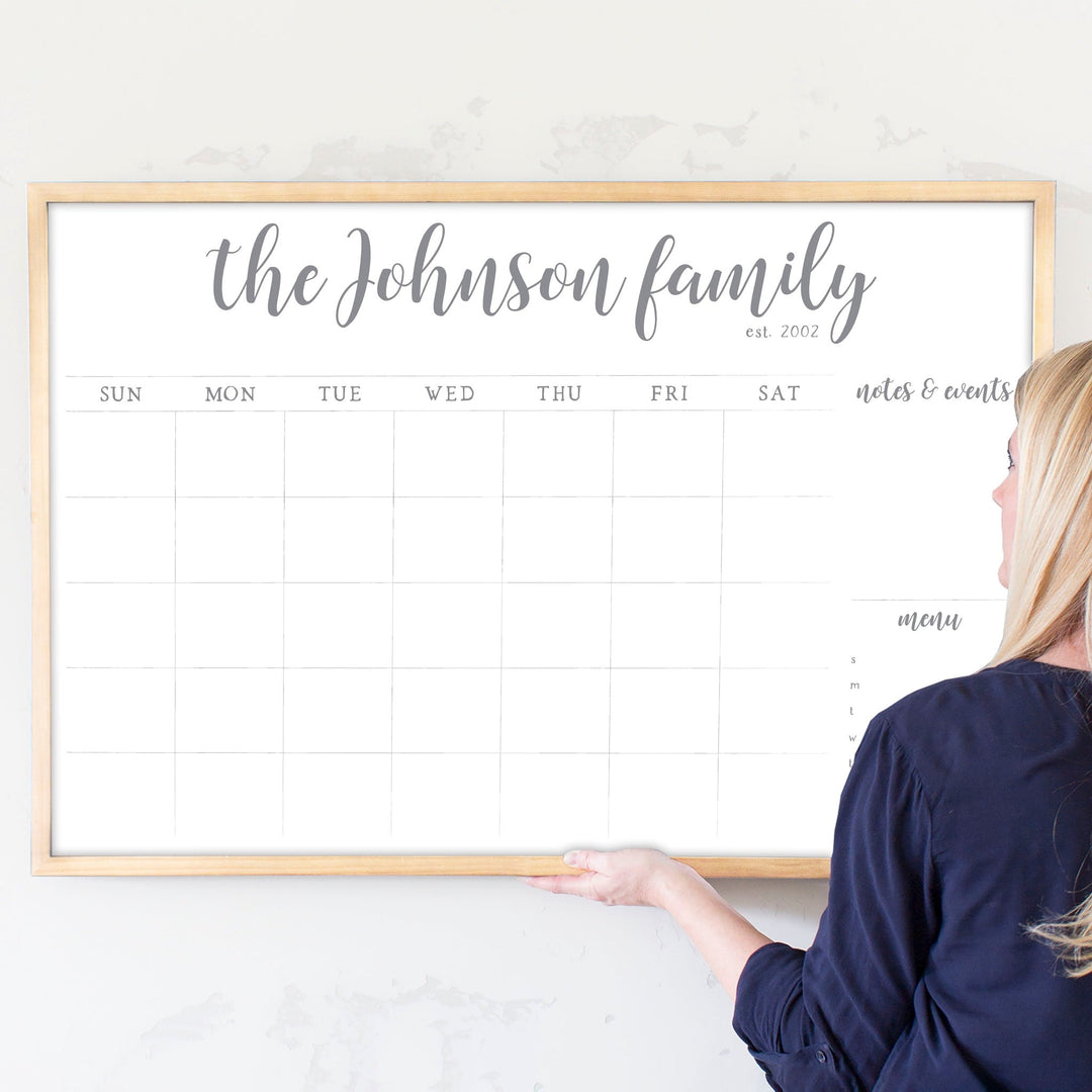 A framed whiteboard monthly calender hanging on the wall