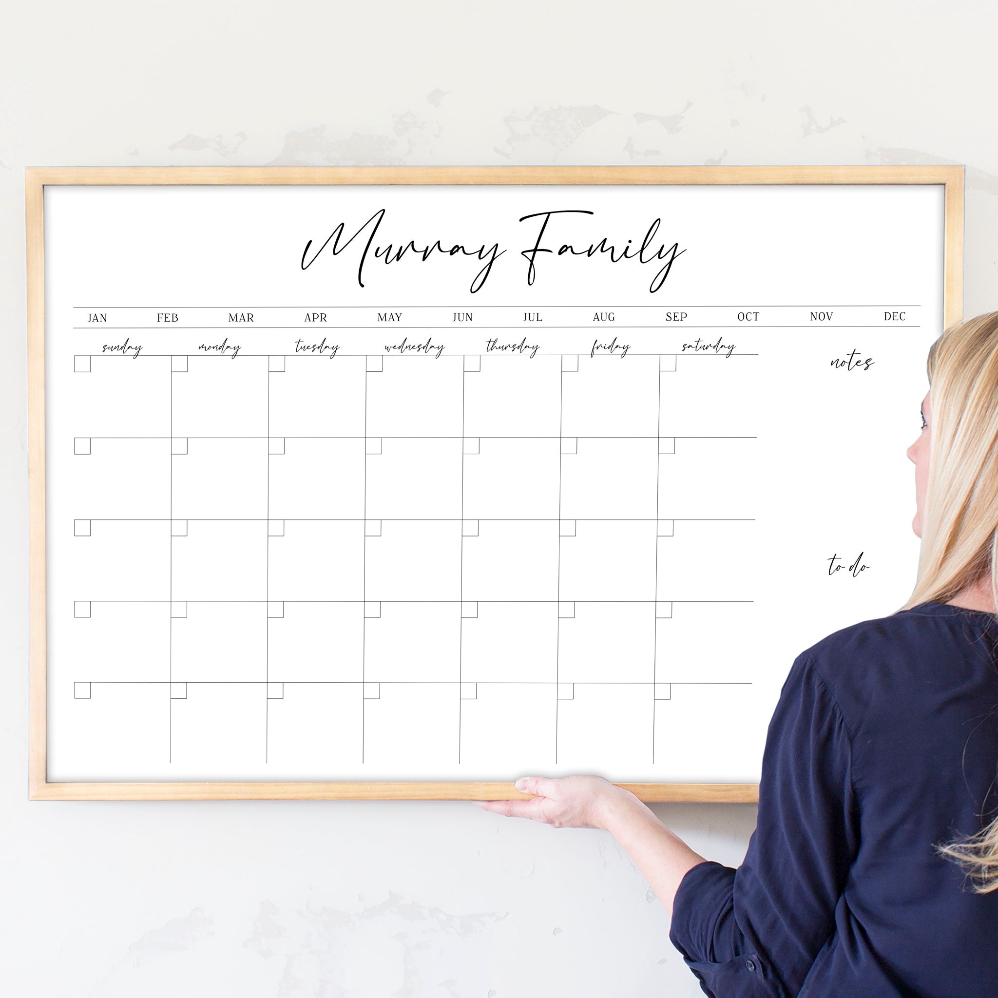 A framed whiteboard monthly calender hanging on the wall