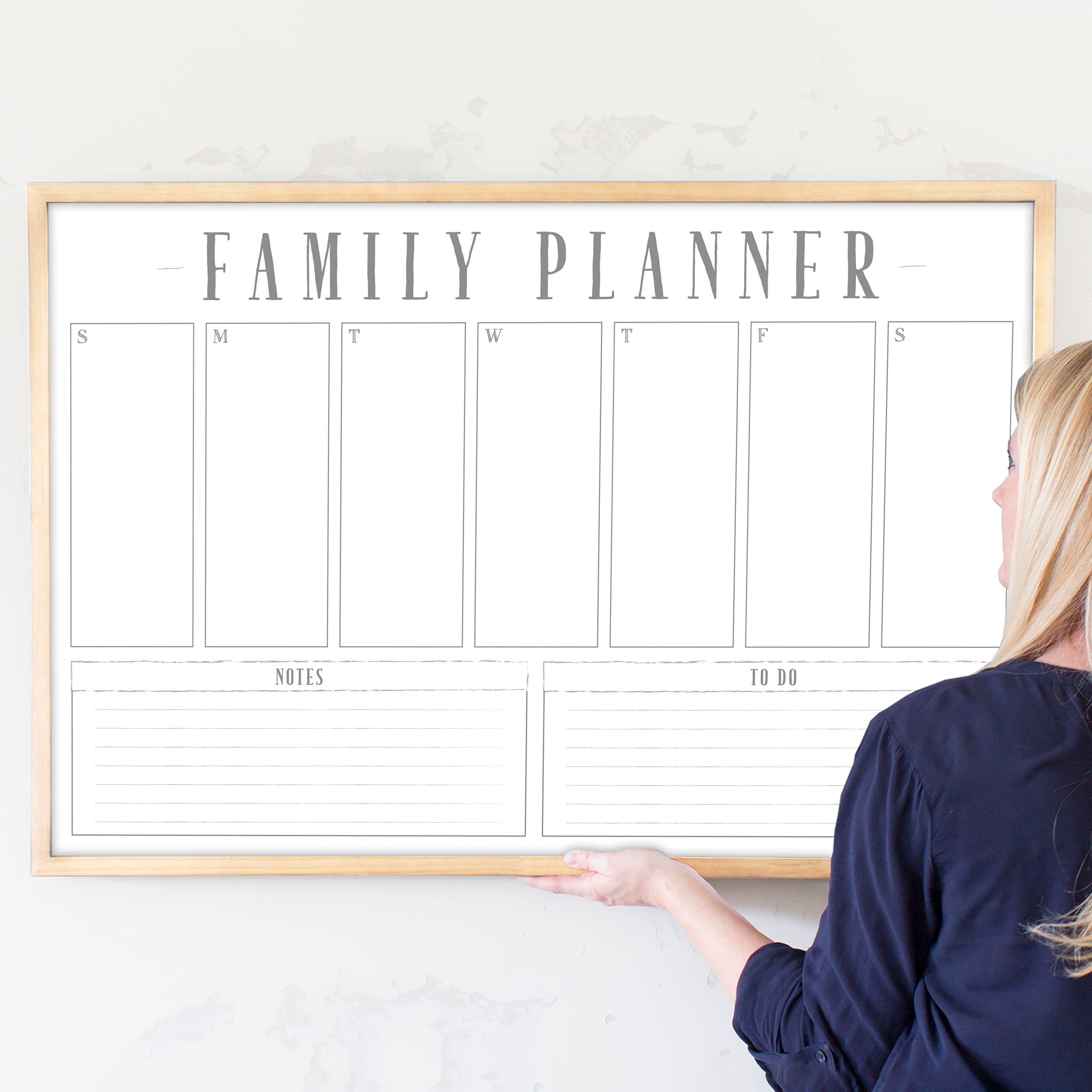 A framed whiteboard weekly calender hanging on the wall