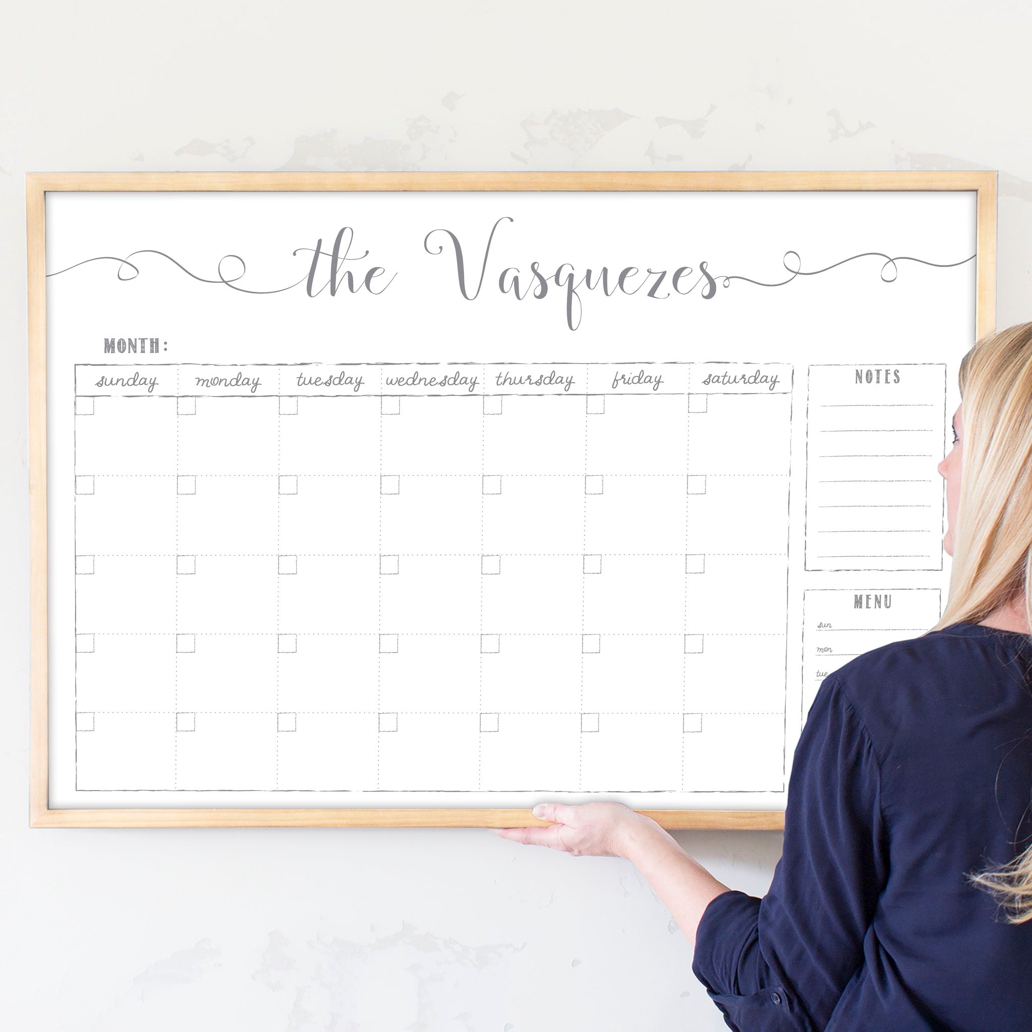 A framed whiteboard monthly calender hanging on the wall