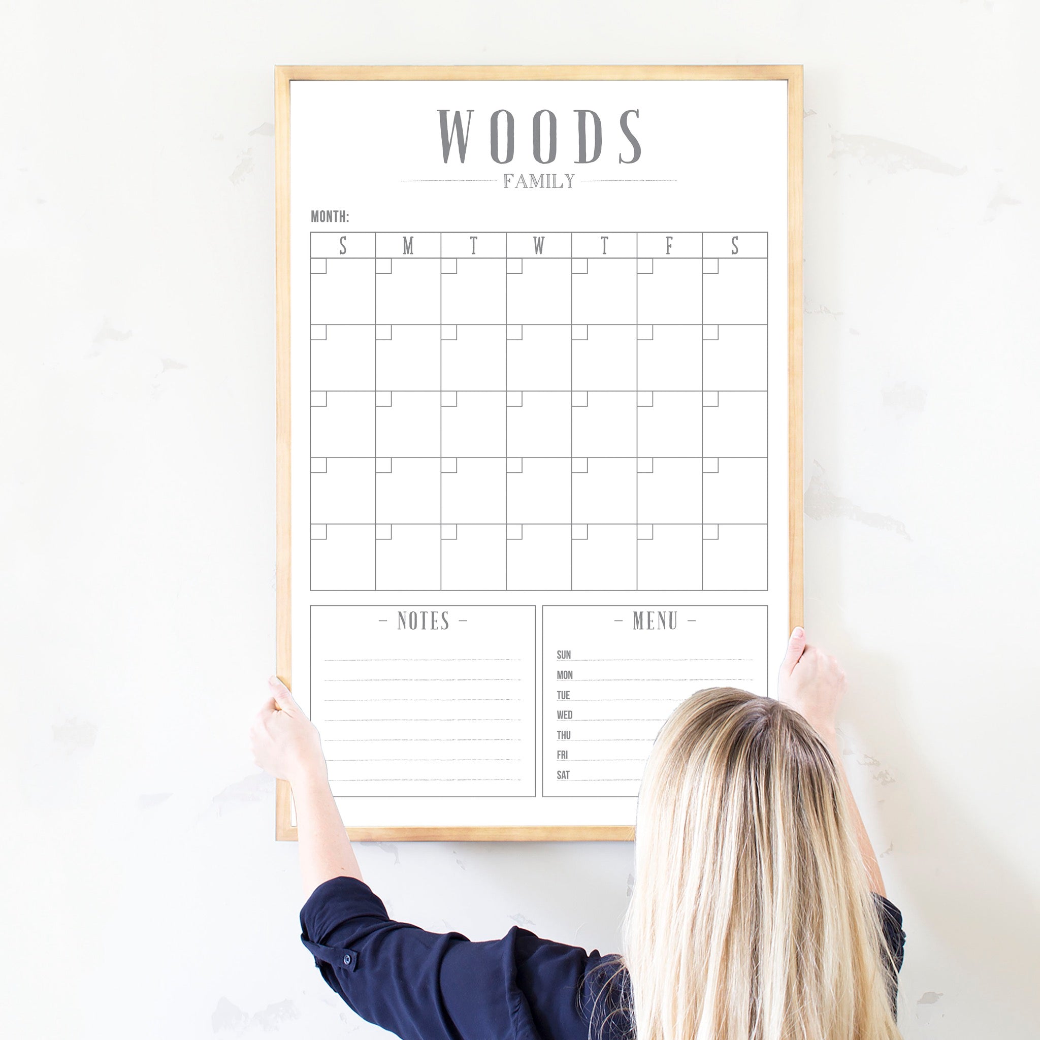 A framed whiteboard monthly calender hanging on the wall