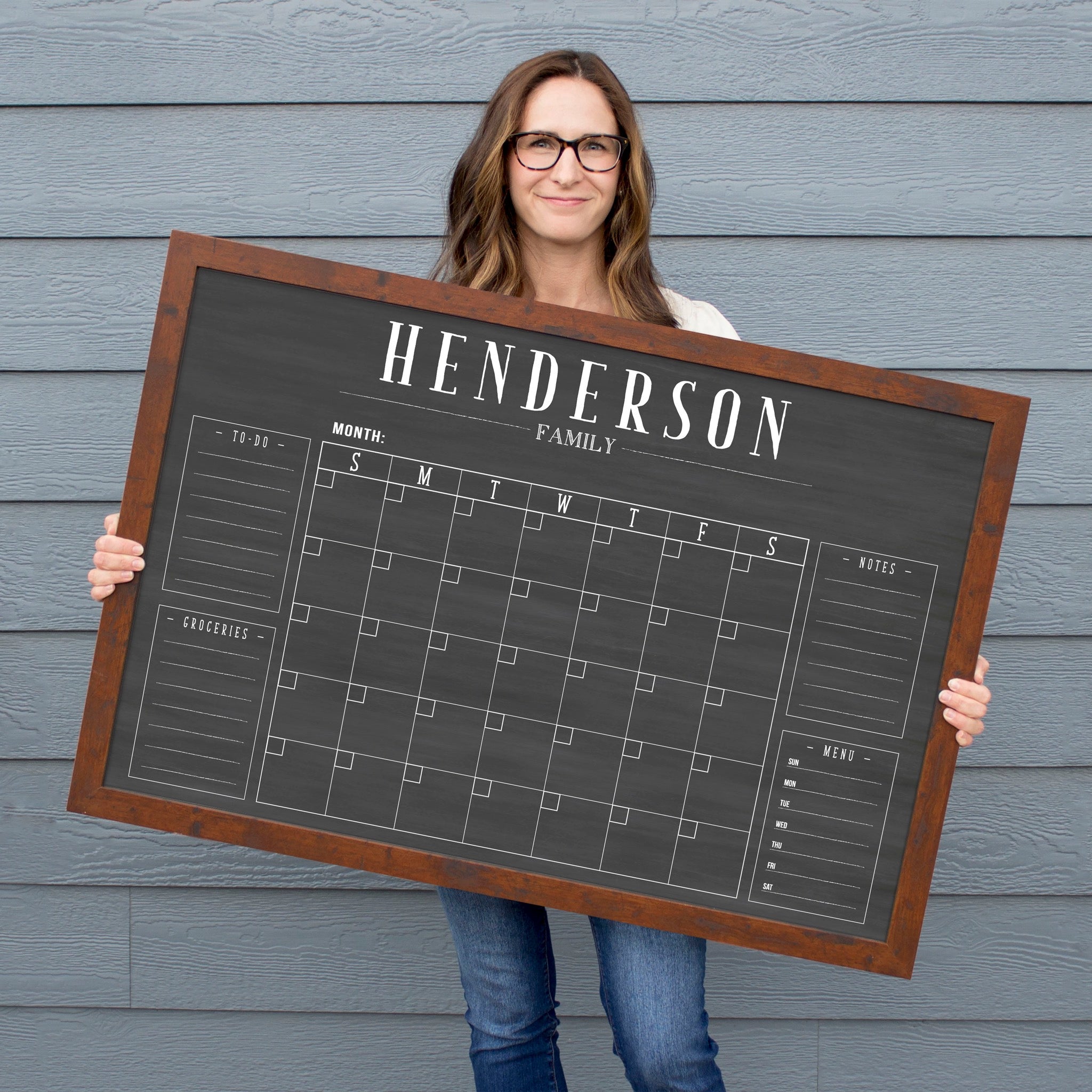 A framed dry-erase family command center with a faux chalkboard look hanging on the wall
