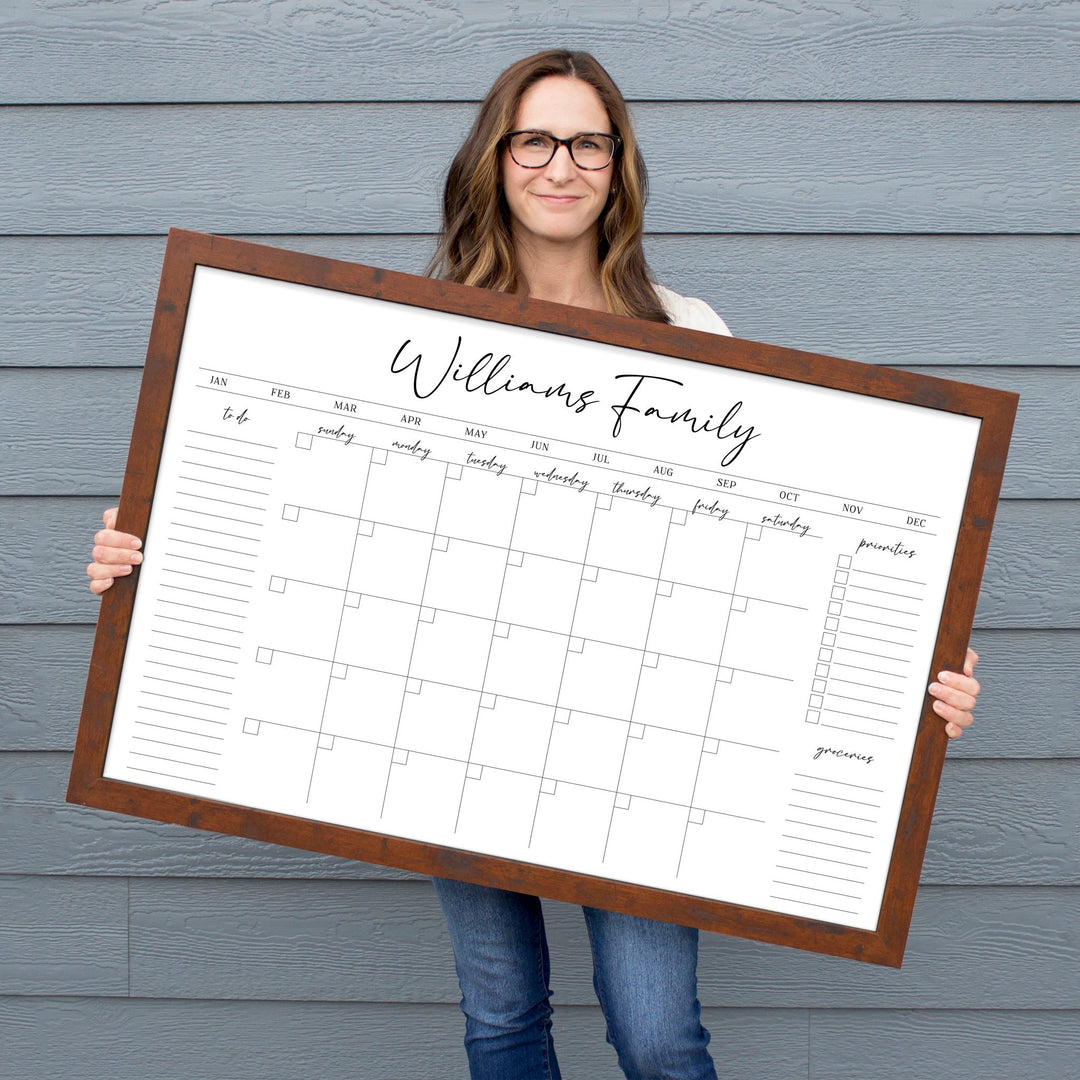 A framed whiteboard monthly calender hanging on the wall