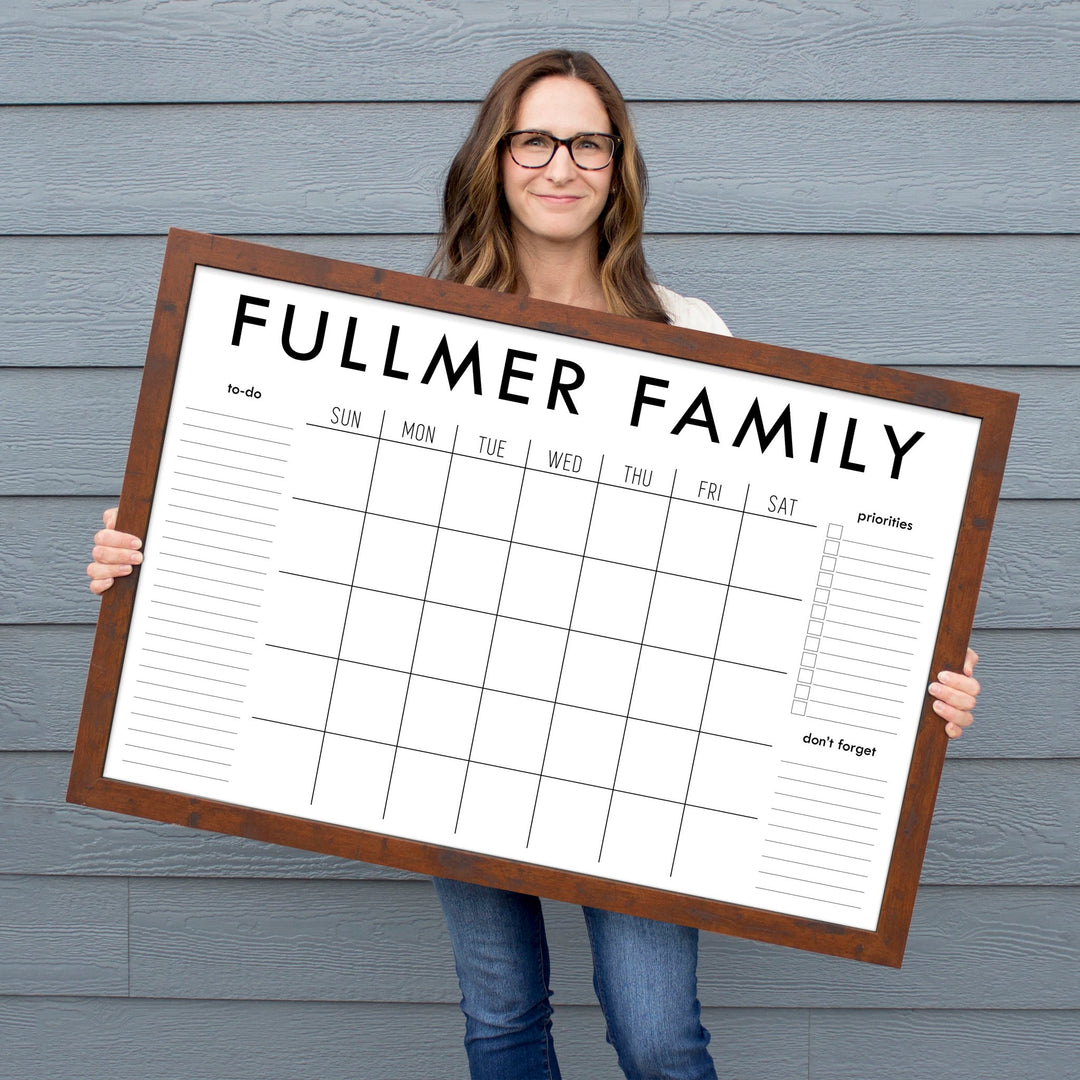 A framed whiteboard monthly calender hanging on the wall