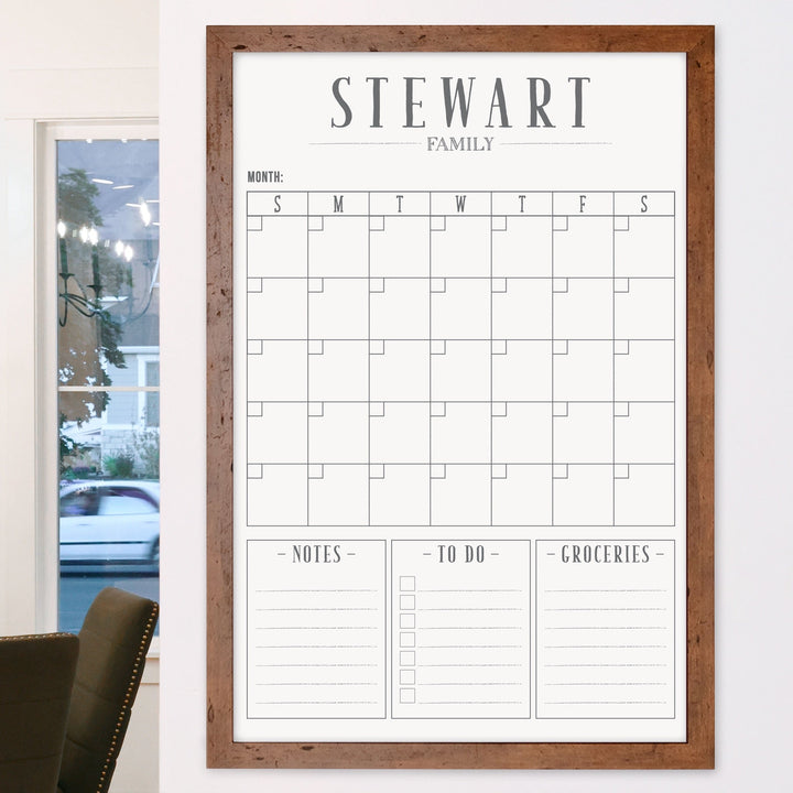 A framed whiteboard monthly calender hanging on the wall