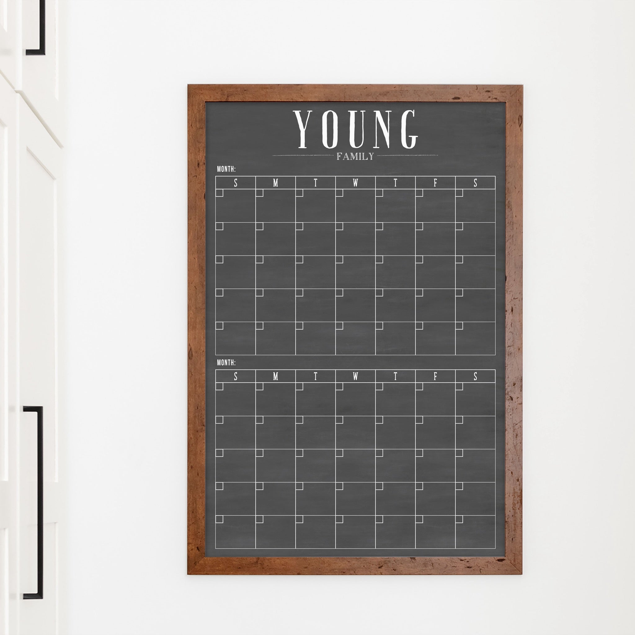 A framed chalkboard dry-erase calendar with a two month design format hanging on the wall