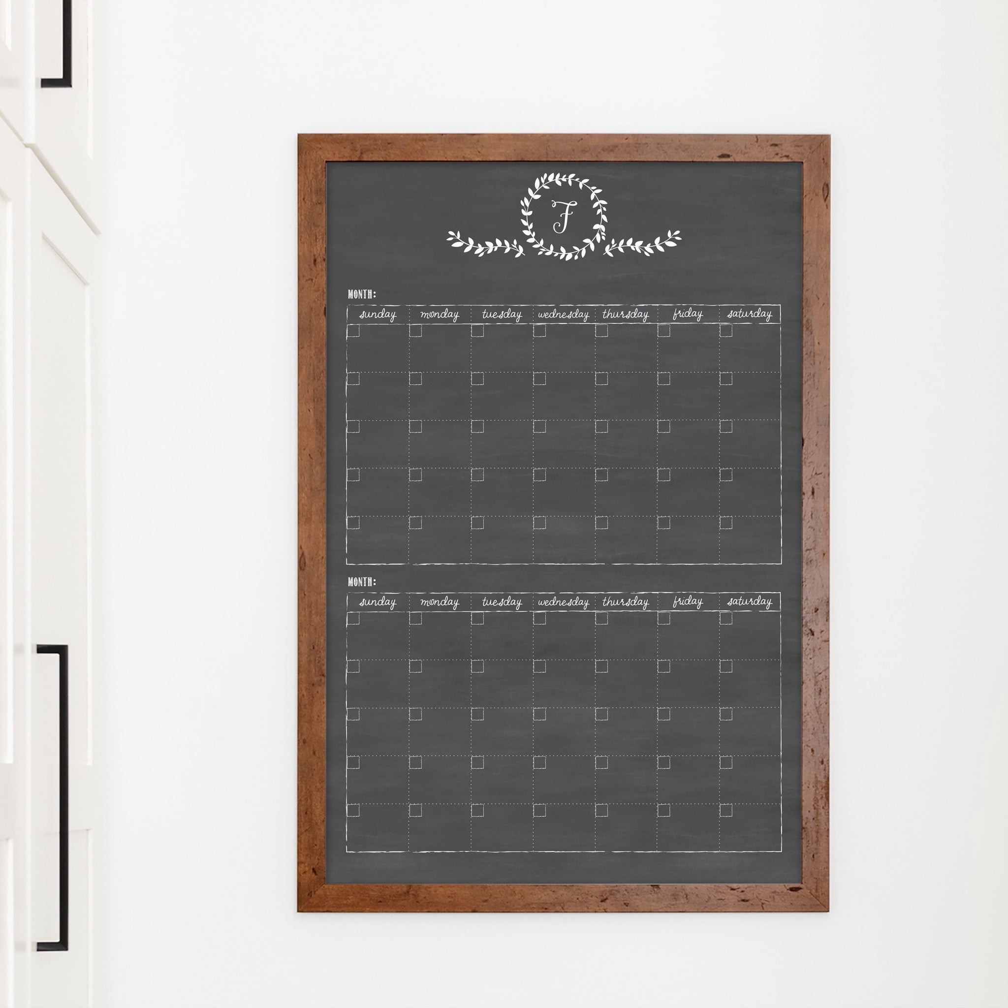 A framed chalkboard dry-erase calendar with a two month design format hanging on the wall