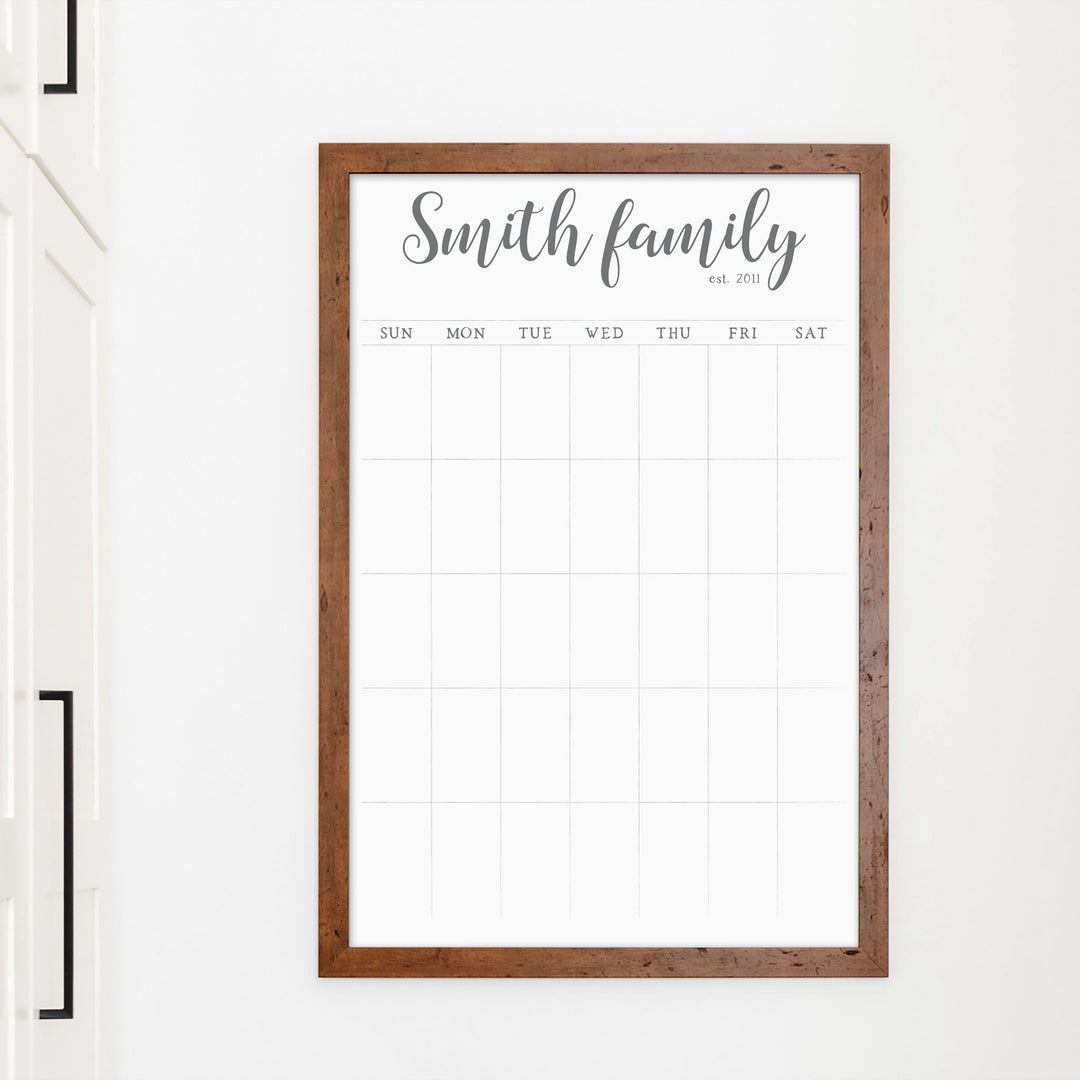 A framed whiteboard monthly calender hanging on the wall